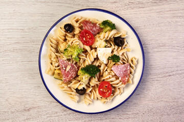 Wall Mural - Bowl of tasty pasta salad with omatoes, ham, black olives, broccoli and cheese 