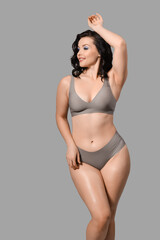 Poster - Beautiful young happy body positive woman in stylish underwear on grey background