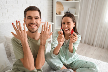 Poster - Young man with applied nail polish and his wife in bedroom