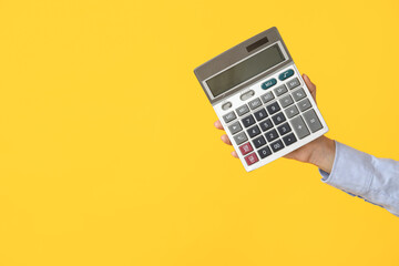 Wall Mural - Female hand with calculator on yellow background