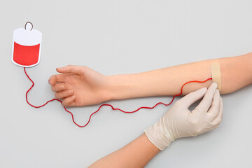 Wall Mural - Female hands with paper blood pack for transfusion on grey background. Donation blood concept.
