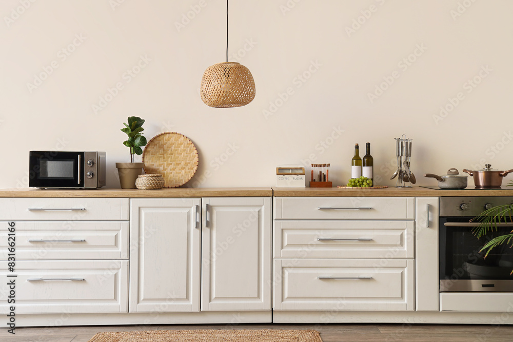 Interior of beautiful kitchen with white counters, microwave, houseplant and lamp
