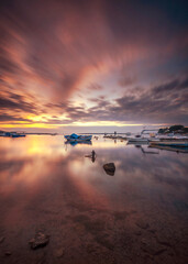 Wall Mural - boats waiting in the reflective water clouds in the sky sunset colors