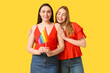 © Pixel-Shot - Beautiful young lesbian couple with LGBT flag on yellow background