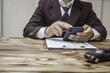 © NanSan - A businessman in a formal suit signs a contract, hands close up, highlighting financial terms like amortization, APR, and asset management, documents symbolizing various loan and insurance concepts.
