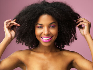 Poster - Afro, haircare and face of black woman, makeup and studio for hairstyle, growth and texture of hair. Pink background, portrait and African girl with happiness for treatment in salon and hairdresser