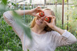 © anna.stasiia - Portrait of blonde woman harvesting red ripe organic tomatoes in greenhouse and having fun. Healthy homegrown food concept. Cottagecore countryside life