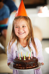 Happy, excited and girl child with birthday cake, smile and hat in classroom for event, party or celebration. Dessert, gift and cheerful kid with chocolate, candle or snack at school with friends