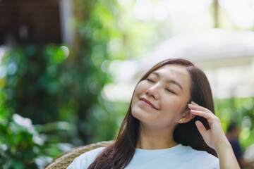 Wall Mural - Portrait image of a young woman with closed eyes enjoying and relaxing in the outdoors