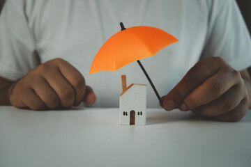 Wall Mural - Man holding orange umbrella protection home symbolizes holistic insurance protection for family, life, health, and house. Distinctly emphasize family life insurance concepts