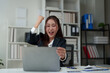 © crizzystudio - Surprised and happy businesswoman shows joyful expression after viewing news results, business approval results and financial approval results on laptop at office. Startup business growth concept.