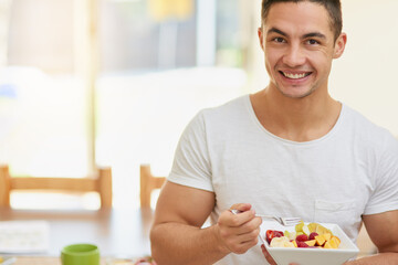 Wall Mural - Man, portrait and eating a fruit salad in home for breakfast with confidence, healthy meal and nutrition in dining room. Person, wellness and nutritionist with organic brunch for vegan diet or mockup