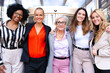 © Raquel - Five businesswomen standing, side by side, holding each other by the waist looking at the camera, happy. Suitable for team, friendship and diversity concepts.