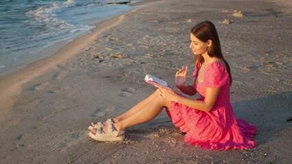 Wall Mural - Beautiful woman reading book on beach in morning. Camera moving around girl