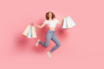 Poster - Full size photo of pretty woman dressed white blouse jeans holding shopping bags fly look empty space isolated on pink color background