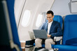 © Nuttapong punna - Asian executive excels in first class, multitasking with digital tablet, laptop and smartphone. Travel in style