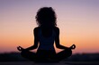 © Mike - A silhouette of a woman meditating in the lotus position, capturing a serene and tranquil moment