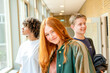 © Connect Images - Three students standing in a school corridor, smiling and posing for the photo with a brightly lit background.
