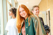 © Connect Images - Three teenagers stand in a school corridor, smiling and looking relaxed, with backpacks suggestive of a break between classes.