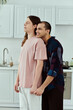 © Bliss - A gay couple in casual clothes standing in a cozy kitchen, sharing a tender embrace.