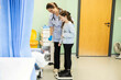 © Connect Images - Nurse assisting a girl on a scale