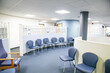 © Connect Images - Empty waiting room with blue chairs and wall-mounted bulletin boards of a medical practice