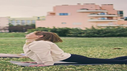 Wall Mural - Yogini bending exercises in city park vertically. Relaxed women practicing yoga