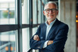 © standret - Confident mature businessman standing by office window