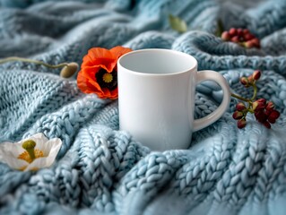 A white mug sits on a blue blanket with red flowers. The concept of warmth and comfort, as the mug and blanket are both associated with relaxation and coziness