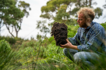 university student conducting research on forest health. farmer collecting soil samples in a test tube in a field. Agronomist checking soil carbon and plant health on a farm in australia