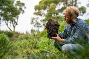 farmer wearing blue shirt and jeans, farmer holding soil, doing soil tests in a home laboratory. Looking at soil life and health