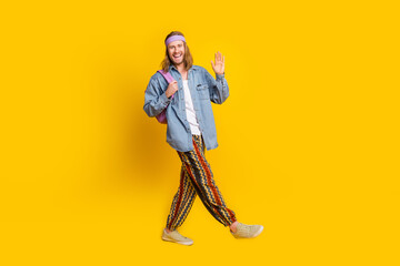 Poster - Full body portrait of cool young man walk arm wave hi empty space wear denim shirt isolated on yellow color background