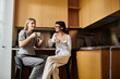 © Bliss - A young lesbian couple enjoys coffee in a cozy kitchen, chatting and sharing a moment at the counter.