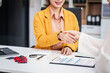 © NanSan - Asian businesswoman shakes hands with a salesman and customer at a desk, discussing car sales, insurance, used car loans, and various finance options, including premiums and coverage types.