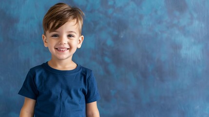 Close up view of a smiling little boy in a t-shirt with accessories on a blue modern background