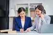 © NanSan - Two Asian businesswomen collaborate on stock market strategies and financial services, exchanging comments and suggestions on loan applications and investment opportunities.