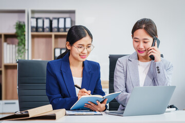 Wall Mural - Two Asian businesswomen collaborate on stock market strategies and financial services, exchanging comments and suggestions on loan applications and investment opportunities.