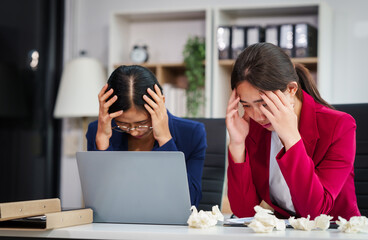 Wall Mural - Two Asian businesswomen under stress and pressure discuss financial matters, experiencing anxiety and worry while navigating the complexities of the stock market and loan applications.