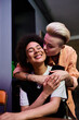 © Bliss - Lesbian couple sharing a loving hug while seated at a cafe table.
