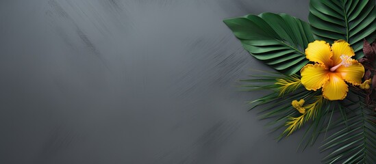 Poster - On a green palm leaf a yellow flower and a flower petal pattern on a gray background with a copy of the space Layout for your ideas Flat lay