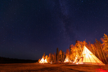 Wall Mural - Amazing starry night sky and milky way galaxy over the light up Tipi or Tepees. Yellowknife, Northwest Territories, Canada.