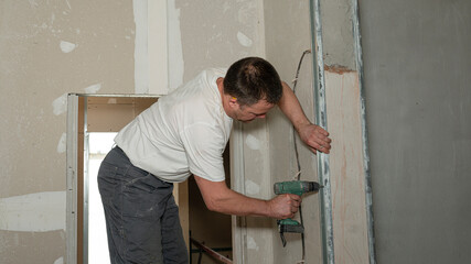 Worker is using a screwdriver hole to drill a hole on a construction site 