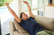 © Lyndon Stratford/peopleimages.com - Stretching, relax and happy man on sofa in home for peace, calm or rest in living room in morning for health. Comfort, energy and person on couch for nap, sleeping and wake up in apartment on holiday