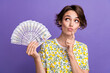 © deagreez - Photo of pretty young woman hold dollar bills look empty space wear t-shirt isolated on violet color background