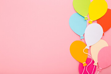 Wall Mural - Colorful balloon shapes from application paper with white strings on light pink table background. Pastel color. Closeup. Empty place for inspirational text, quote or sayings. Top down view.