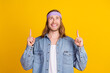 © deagreez - Photo portrait of attractive young hippie man point look up empty space wear trendy denim outfit isolated on yellow color background