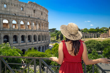 brunette girl with straw hat admires the majesty of the colosseum and in the background the ancient 