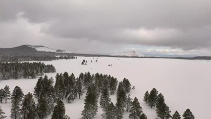 Wall Mural - Flying over a snow-covered field with snow capped mountains in the distance over northern Arizona