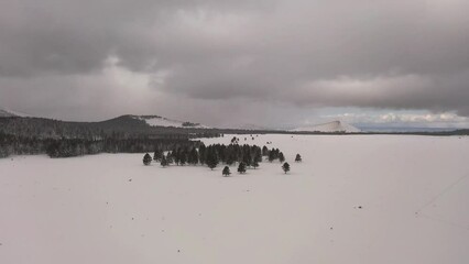 Wall Mural - Flying over a snow-covered field with snow capped mountains in the distance over northern Arizona