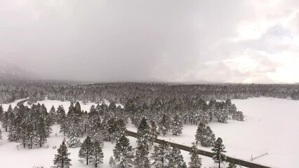 Wall Mural - Flying over a snow-covered field with snow capped mountains in the distance over northern Arizona